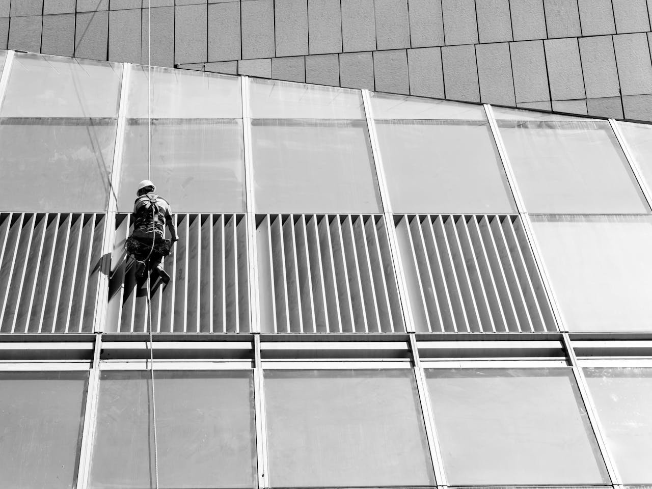 about-us A window cleaner hangs on a high-rise building, showcasing urban maintenance.